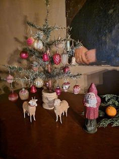 a small christmas tree with ornaments on it and an old fashioned santa clause figurine next to it