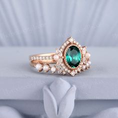 a close up of a ring with an emerald colored stone and pearls on the side