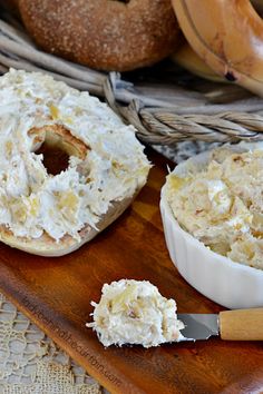 a wooden tray topped with doughnuts covered in white frosting next to a basket of bagels