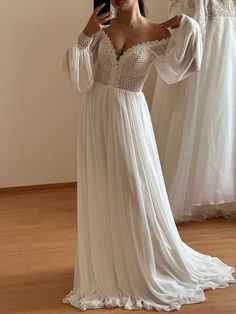 a woman is taking a selfie in front of her wedding gowns and looking at her phone