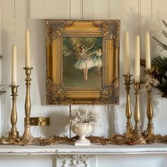 a mantle with candles and a painting on it