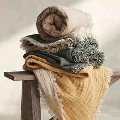 a pile of blankets sitting on top of a wooden bench