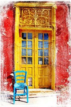 a blue chair sitting in front of a yellow door on the side of a building