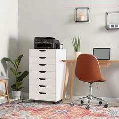 a room with a desk, chair and printer on it in front of a wall