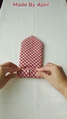 two hands are holding a red and white checkered paper bag with the words made by apri on it