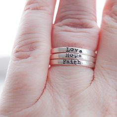 Sterling Silver Skinny Rings Faith, Hope, Love Skinny Rings that are handcrafted and sterling in every sense. They're more than jewelry—they're a daily nod to what matters. Jewelry with Meaning In a whirlwind world, these rings serve as a quaint little reminder of what sticks - faith, hope, and love. Each ring carries its own potent reminder, stamped thoughtfully into its subtle shine. Stack ‘em or Solo ‘em Their sleek design allows them to be your right-hand, er, ring for any occasion. Dress th Inspirational Personalized Sterling Silver Rings, Inspirational Hand Stamped Silver Rings, Inspirational Adjustable Sterling Silver Rings, Adjustable Inspirational Sterling Silver Rings, Inspirational Adjustable Ring, Inspirational Adjustable Hand Stamped Rings, Nickel-free Meaningful Promise Ring, Adjustable Inspirational Rings For Everyday, Inspirational Adjustable Silver Rings