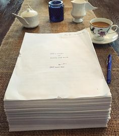 a stack of papers sitting on top of a table next to cups and saucers