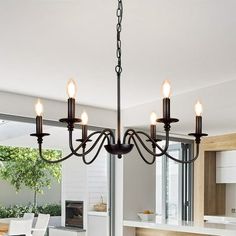 a chandelier hanging from the ceiling in a kitchen with an open dining room