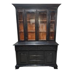 an old black china cabinet with glass doors on the front and bottom, is against a white background