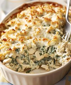 a casserole dish with chicken and spinach in it on a tablecloth