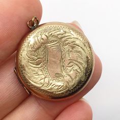 Lovely, rolled gold, locket from around the early 1900s judging by the style. It has old photos from the 1940s but the locket looks older. The gold finish on this locket has some wear, particularly on the back. It measures 2.7 cm ( 1.1 inch ) across. Ornate Medallion Locket Necklace With Vintage Charm, Antique Gold Medallion Locket Necklace With Vintage Charm, Victorian Round Locket Necklace Stamped 14k, Antique Medallion Locket Necklace Stamped 14k, Antique Bronze Locket Necklace With Round Pendant, Antique Bronze Round Locket Necklace, Antique Bronze Round Pendant Locket Necklace, Vintage Medallion Locket Necklace With Coin Pendant, Victorian Medallion Locket Necklace With Vintage Charm