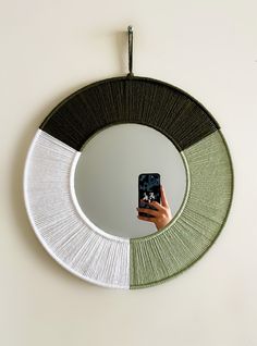 a hand holding a cell phone in front of a circular mirror with different colors on it