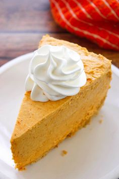 a slice of pumpkin pie with whipped cream on top sits on a white plate, ready to be eaten