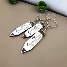 three personalized metal key chains with two knives on them and a flower in the background