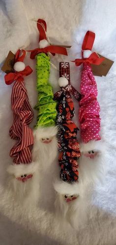 small christmas tree ornaments are lined up on a white furnishing area with red and green ribbons