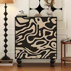 a black and white cabinet sitting on top of a wooden floor next to a lamp