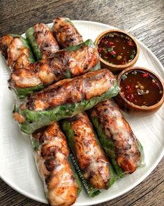 chicken wrapped in lettuce on a plate with dipping sauces next to it