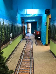 there is a train track going down the middle of this hallway with trees on both sides