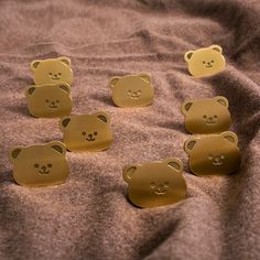 six gold bear magnets sitting on top of a brown blanket next to each other