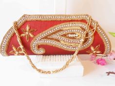 "A red clutch bag with gold bead trim. The statement handbag has a background of red taffeta, this is a brownish red. The front flap has a stunning design of gold and copper beading with rhinestones. The bag interior is red with one zipper pocket and a snap closure. The red beaded clutch also includes a beaded strap to wear on shoulder. This is a dazzling special occasion bag. It is large enough to hold an iPhone. MATERIAL: Beading, taffeta CONDITION: Good SIZE: 11\" wide and45: high COLOR: Brow Red Embellished Rectangular Bag, Red Embellished Bag For Formal Occasions, Formal Red Embellished Bag, Red Beaded Rectangular Evening Bag, Red Embellished Clutch For Formal Occasions, Elegant Red Beaded Bag, Elegant Red Beaded Shoulder Bag, Red Pouch Clutch For Festivals, Red Embellished Bag As A Gift