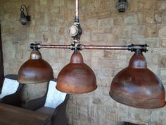 three industrial style lamps hanging from a brick wall