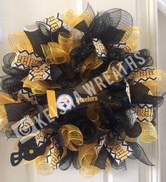 the wreath is decorated with black, yellow and white mesh ribbons that are attached to a door