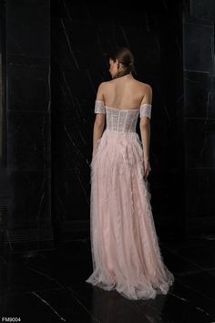 a woman in a pink dress standing on a black marble floor with her back to the camera