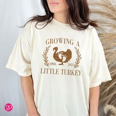 Thanksgiving Baby Reveal Shirt, Growing a Little Turkey with Date Comfort Colors® Shirt, Personalized Fall Shirts *  OUR PROCESS * We print our shirts by hand with 100% eco-friendly water based inks on premium Comfort Colors tees.  Water based inks produce a super soft, breathable print with unmatched comfort and durability. We DO NOT USE vinyl.   * SIZING * Please see images with sizing chart details. Comfort Colors tees are a unisex fit. WOMEN For a relax fitting tee order the size you normally wear. If you would like a more fitted look then order a size down.   MEN This shirt style runs true to size. Order your regular size. * MATERIAL * 100% Ring Spun Cotton Preshrunk, Soft-Washed, Garment-Dyed Fabric * CARE * Due to the nature of this t-shirt dying process, it is best to wash separate Baby Reveal Shirt, Thanksgiving Baby, Baby Reveal, Comfort Colors Shirt, Comfort Colors Tee, Fall Shirts, Comfort Colors, Fabric Care, Shirt Style