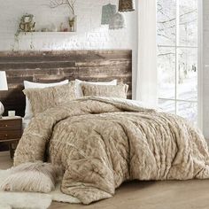 a bedroom with white brick walls and wood flooring is decorated in neutral tones, including an overstuffed bed