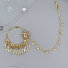 a pair of gold earrings with pearls hanging from the end of each earring, on top of a white cloth