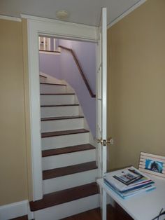 there is a small table with magazines on it in front of the door and stairs