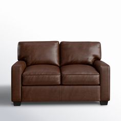 a brown leather loveseat against a white wall with no one on it's legs