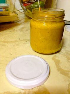 a jar of mustard sitting on top of a counter next to a plastic container with a straw sticking out of it