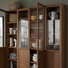 an open cabinet with dishes and cups on it in a room that has wood paneling