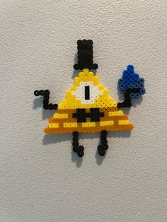 a piece of art made out of legos on a white wall next to a blue and yellow object