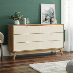 a white dresser sitting on top of a hard wood floor next to a green wall