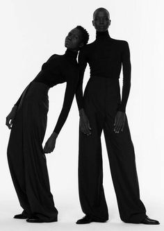 two black women standing next to each other in front of a white background with one woman touching her face