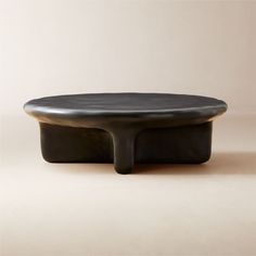 a black coffee table sitting on top of a white floor next to a beige wall