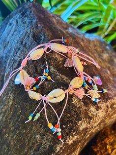 the bracelet is decorated with flowers and beads on it's side, sitting on a rock in front of some plants