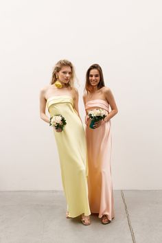 two women standing next to each other wearing dresses and holding bouquets in their hands