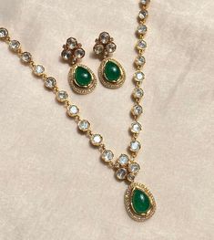 Emerald Kundan Necklace set featuring brilliant green Polki and lustrous Kundan stones, this exquisite necklace is a masterpiece of jewelry craftsmanship. Its timeless design blends traditional charm with contemporary elegance, making it a perfect choice for special occasions. The set includes a matching necklace and earrings, exuding a regal aura that's perfect for weddings, parties, and cultural celebrations. Elevate your style with this stunning Pakistani necklace that captures the essence of Luxury Green Stone Work Sets, Luxury Gold Emerald Necklace For Diwali, Luxury Green Kundan Necklace For Ceremonial Occasion, Luxury Gold Chandbali Emerald Necklace, Luxury Green Hand Set Chandbalis, Luxury Hand Set Green Chandbalis, Luxury Green Temple Jewelry Chandbalis, Pakistani Necklace, Diamond Pendant Set