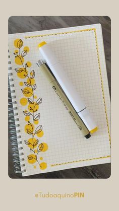 a pen sitting on top of a notebook next to a flowered paper pad with yellow flowers