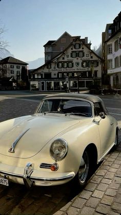 an old white car is parked on the side of the road in front of some houses