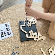 a woman is working on a clock made out of wood and metal gears with screwdrivers