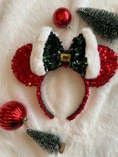 a minnie mouse ears headband with red and green sequins on it, surrounded by christmas ornaments