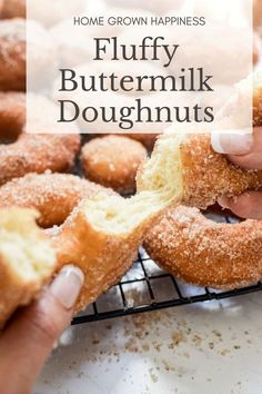 a person holding a half eaten doughnut in front of other donuts on a cooling rack