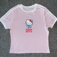 a pink hello kitty t - shirt sitting on top of a floor