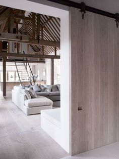 a living room filled with furniture next to a tall wooden wall covered in wood planks