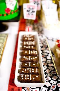 a table topped with brownies covered in white frosting next to cards and dice