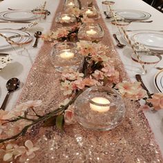 a long table is set with candles and flowers in glass vases on top of it